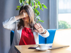 professional woman hiding eyes from visual harassment on her laptop